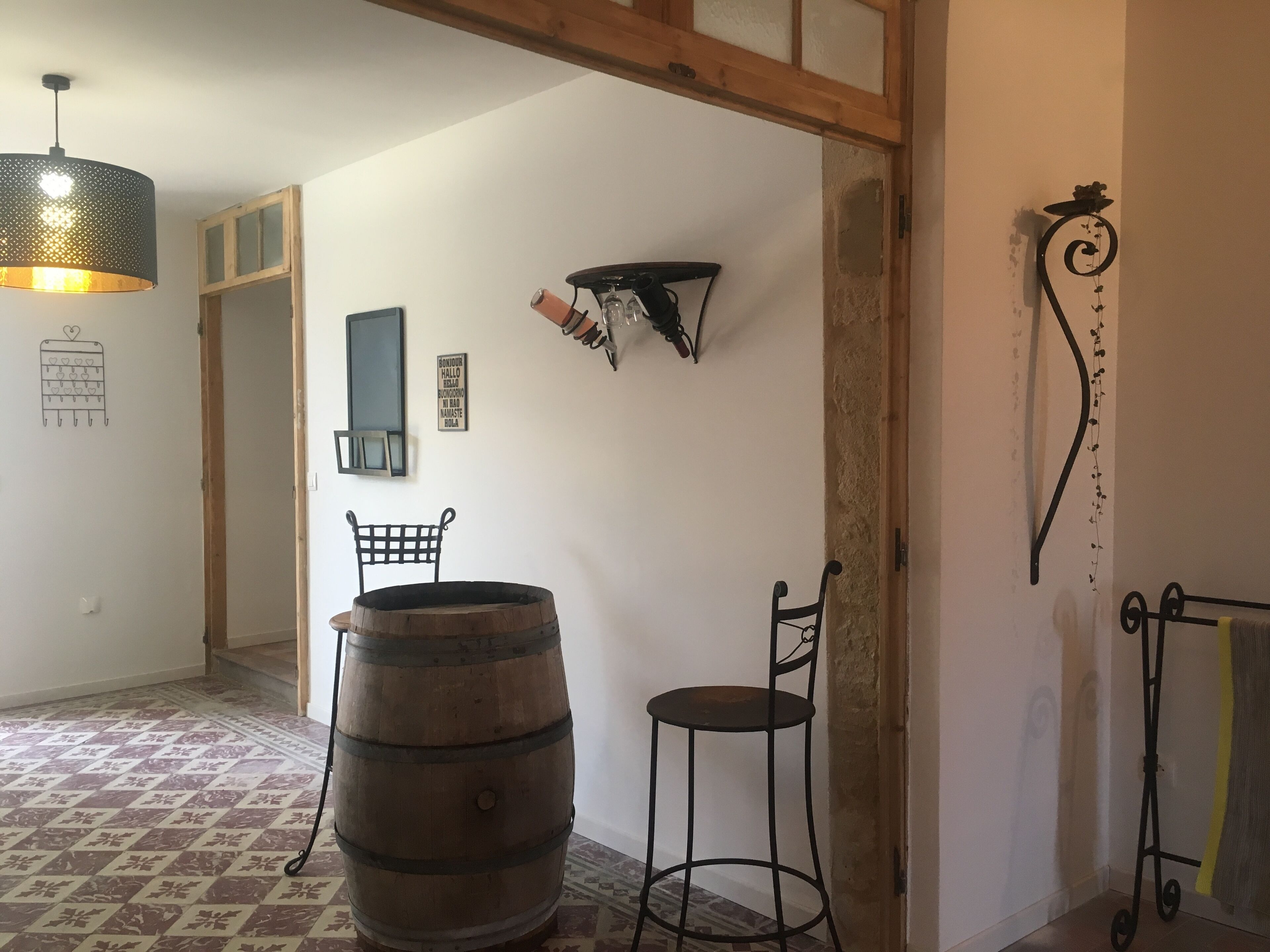 A room with a wooden barrel, a metal chair, a hanging light fixture, and a wall-mounted shelf with decorative items.