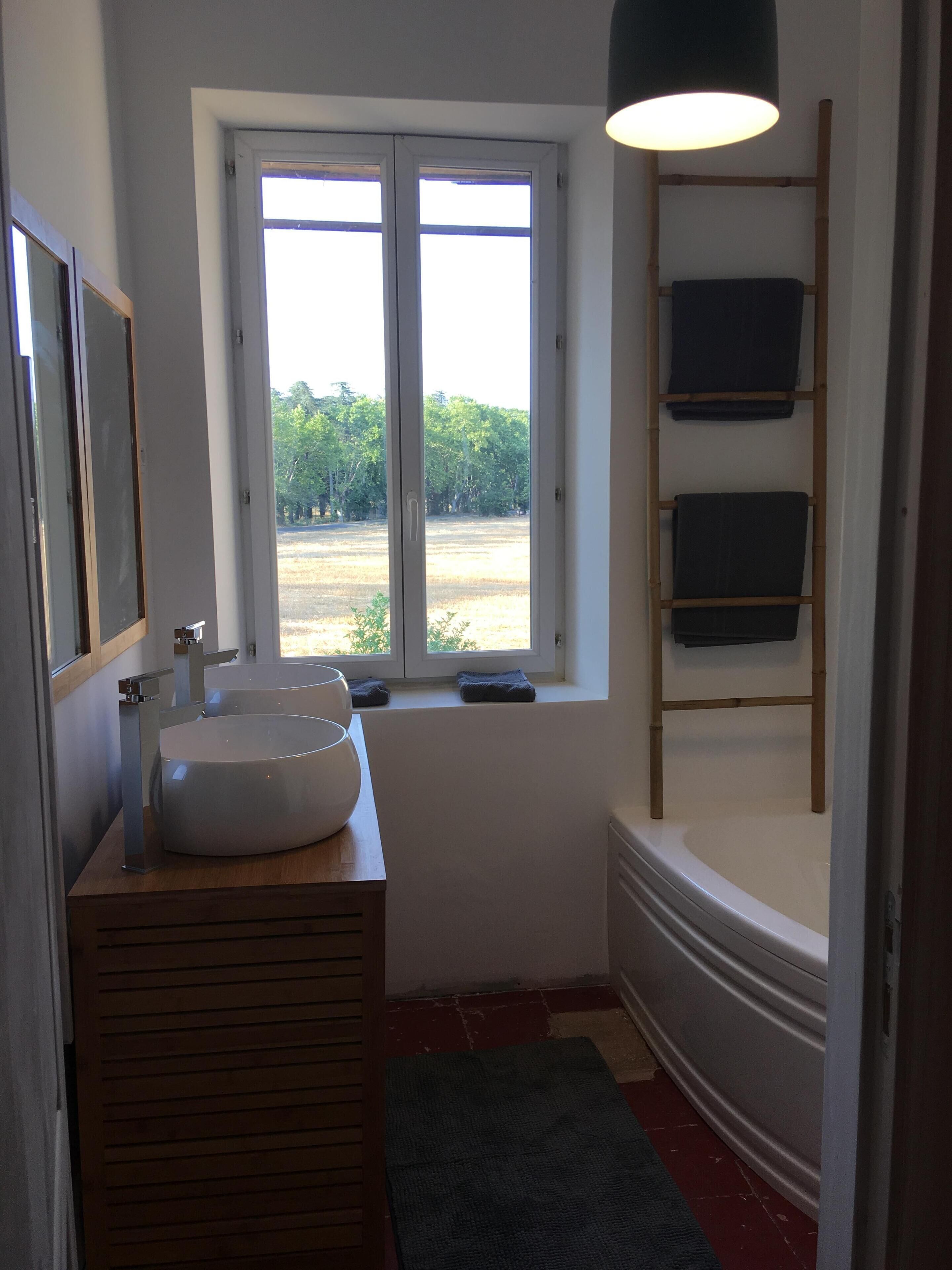 A bathroom with a large window, a sink, and a towel rack.