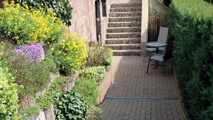 A paved pathway leading to a building entrance with a small outdoor seating area.