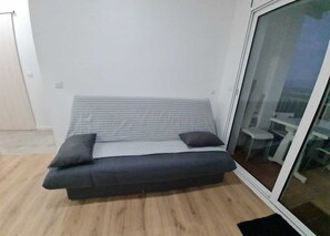 A small, modern room with a bed, a glass door, and a view of the outdoors. - Apartment for 4 people, OCEAN VIEW, 100 meters from the beach + private PARKING + AIR CONDITIONING (L'Escala)