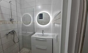 A bathroom with a shower, two sinks, and two round mirrors.