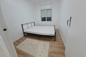 A small, single-bed room with a window, a door, and a light-colored rug on the floor. - Apartment for 4 people, OCEAN VIEW, 100 meters from the beach + private PARKING + AIR CONDITIONING (L'Escala)