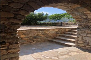 Una escalera de piedra que sube a un nivel superior, rodeada de muros de piedra y con una vista despejada del cielo y el paisaje lejano.