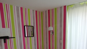 A room with a bed, a green side table, a mirror, and a wall with vertical stripes. - STUDIO 1 PERSON - CENTER LA BAULE (La Baule)