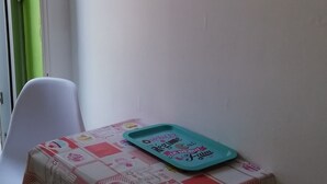 A small table with a colorful tablecloth, a teal tray, and a wall decoration with flowers and the word "Flowers". - STUDIO 1 PERSON - CENTER LA BAULE (La Baule)
