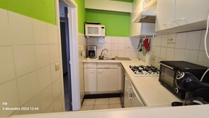 A compact kitchen with white cabinets, a microwave, a gas stove, and a coffee maker.