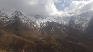 Paisagem montanhosa com picos nevados e uma aldeia com edifícios tradicionais.