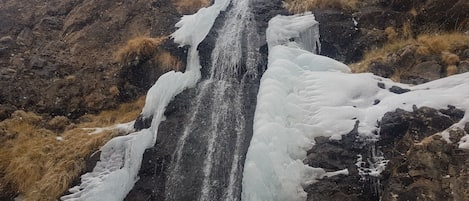 A waterfall cascading over a rocky cliff surrounded by dry grass.