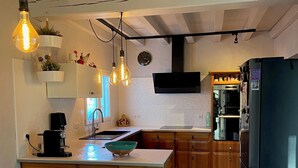 Une cuisine moderne dotée d’un îlot central, de luminaires suspendus, d’armoires en bois et d’un réfrigérateur noir.