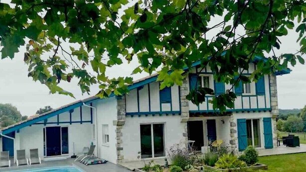 Une maison à deux étages avec une piscine, un patio couvert et un jardin.