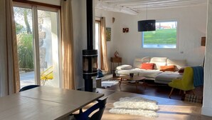 Un salon spacieux avec une grande table, des chaises, un canapé et une cheminée.