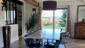 Un espace repas moderne avec une grande table, des chaises bleues et un luminaire suspendu.