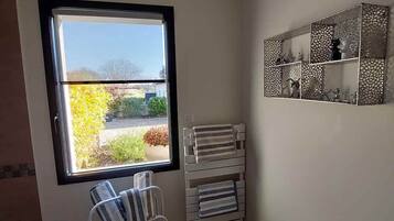 A bathroom with a large window, a towel rack, a chair, a small table, and a decorative mirror.