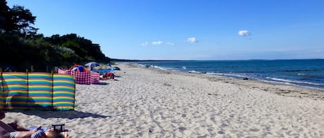 A sandy beach with umbrellas and beach chairs.