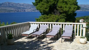 A balcony with four sun loungers and a bench, overlooking a body of water and mountains. - few minutes to the beach (Postira)