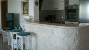A kitchen with a stone countertop, white cabinets, a stainless steel oven, and two bar stools. - few minutes to the beach (Postira)