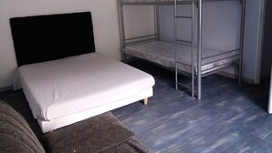 A room with a single bed, a bunk bed, and a couch. - renovated holiday home - sleeps 8 (FLAVIAC)