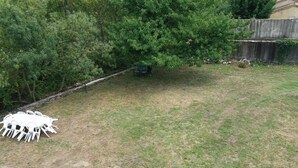 A grassy backyard with a white table and chairs set up. - renovated holiday home - sleeps 8 (FLAVIAC)