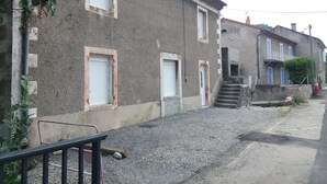 A residential building with a gravel driveway, a staircase leading to a second-floor entrance, and a visible door. - renovated holiday home - sleeps 8 (FLAVIAC)