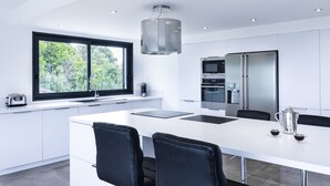 A modern kitchen with a large island, white cabinetry, and stainless steel appliances.