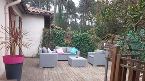 Une terrasse extérieure avec des meubles en osier, une plante en pot et une plateforme en bois.