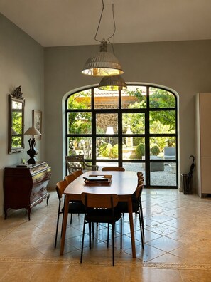 A dining area with a large arched window, a wooden table, and chairs.