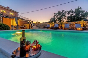 A swimming pool with lounge chairs and a bottle of wine on a tray. - Villa ****, barbecue, free wifi, suitable for family (Štokovci)