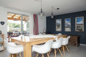 A dining area with a wooden table, white chairs, and a view of the outdoors through large windows. - Villa ****, barbecue, free wifi, suitable for family (Štokovci)