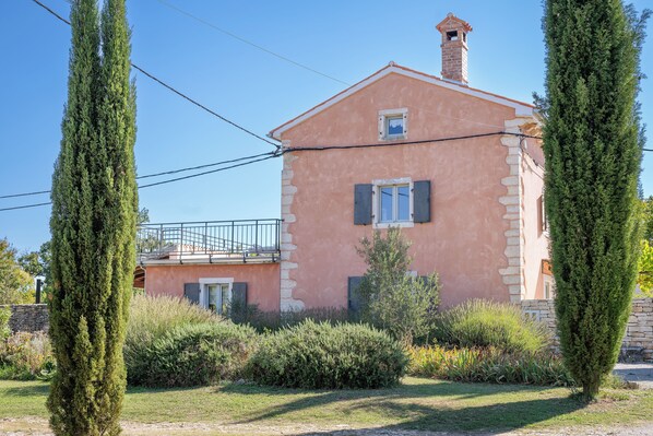 A pink building with a balcony, surrounded by greenery and a stone wall. - Villa ****, barbecue, free wifi, suitable for family (Štokovci)