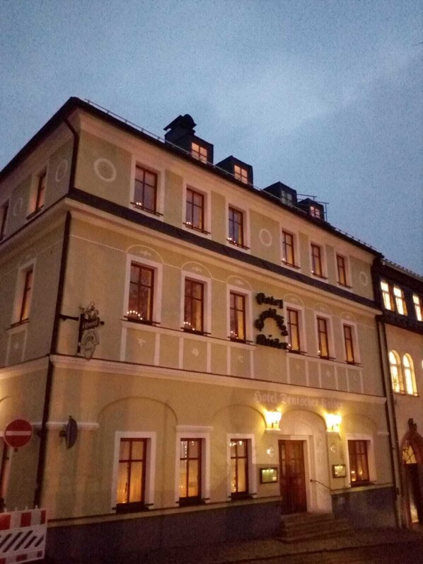 A historic hotel with a classic European architectural style, featuring a symmetrical facade, multiple windows, and a prominent entrance with a staircase.