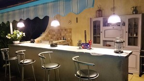 Un espace bar avec des tabourets, un comptoir et un meuble avec des portes en verre.