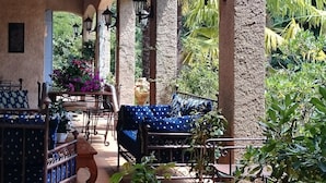 Un patio couvert avec un mur en pierre, un canapé bleu et des plantes en pot.