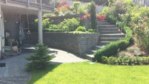 Een tuin met een beplante rand, een klein gazon en een stenen muur.
