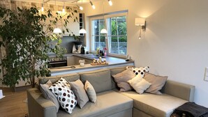 Een moderne woonkamer met een grijze modulaire bank, een klein rond tafeltje en een grote potplant.