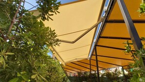 A covered outdoor area with yellow canopies and green foliage.