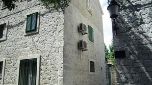 A narrow street with stone buildings, a gate, and a lamp post.