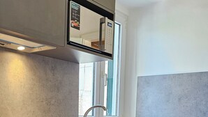 A modern kitchen with a built-in oven, a stainless steel sink, and a window above the sink.