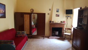 Una sala de estar con un sofá rojo, un aparador de madera, una chimenea y un televisor.