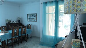 A dining area with a table set for four, a wooden cabinet, and a wall-mounted sign with directional information. - 3 room apartment on the ground floor of a villa with sea view (Mandelieu-La-Napoule)