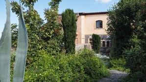 A building with a stone facade and a window, surrounded by lush greenery and a gravel path. - Charming cottage with a unique view (Episkopi Rethymnon)