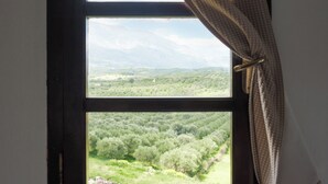 A window with a view of a mountainous landscape and a forested area. - Charming cottage with a unique view (Episkopi Rethymnon)