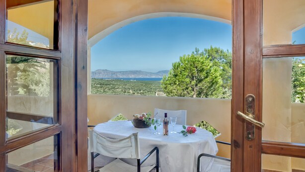 A balcony with a table set for two, a bottle, and a bowl of fruit. - Charming cottage with a unique view (Episkopi Rethymnon)
