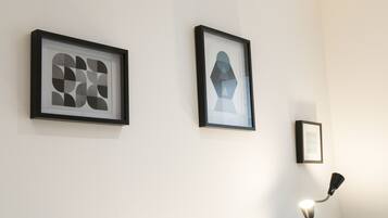 Two framed artworks on a wall, a lamp, and a partially visible framed picture.