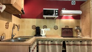 Eine Küche mit Mikrowelle, Wasserkocher und Kaffeemaschine auf der Arbeitsfläche.