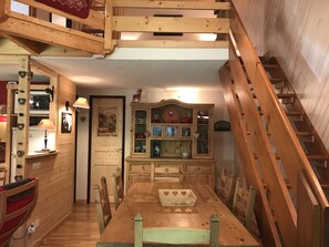 A wooden dining area with a table and chairs, a staircase, and a cabinet with glass doors. - Appartement 65m2 esprit Chalet. Parking. Balcon (Cauterets)