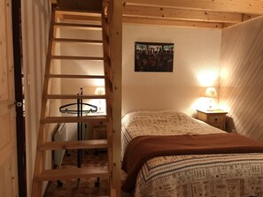 A bedroom with a wooden ladder leading to a loft, a bed with patterned bedding, two bedside tables with lamps, and a wall-mounted picture. - Appartement 65m2 esprit Chalet. Parking. Balcon (Cauterets)