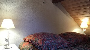 Ein Schlafzimmer mit schrägen Wänden, floralem Bettbezug und Nachttischlampen.