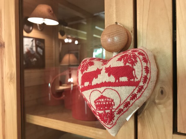 A heart-shaped knitted ornament with a red and white pattern, hanging on a wooden door. - Appartement 65m2 esprit Chalet. Parking. Balcon (Cauterets)