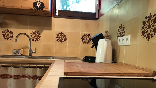 Eine Küche mit Spüle, einer Kaffeemaschine und dekorativen Schneeflockenfliesen an der Wand.