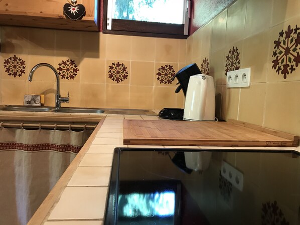 Una cocina con un lavamanos, una cafetera y azulejos decorativos con copos de nieve en la pared.